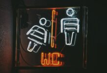 Toaleta i autyzm: jak wspierać naukę korzystania z WC bez presji Neonowy znak toalety z ikonami kobiety i mężczyzny w ciemności
