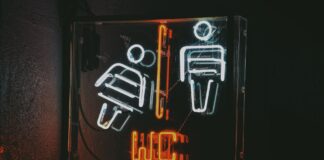 Neonowy znak toalety z ikonami kobiety i mężczyzny w ciemności