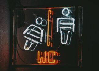 Toaleta i autyzm: jak wspierać naukę korzystania z WC bez presji Neonowy znak toalety z ikonami kobiety i mężczyzny w ciemności